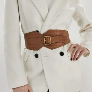 Close-up of brown crocodile embossed wide belt with retro golden square buckle on white suit