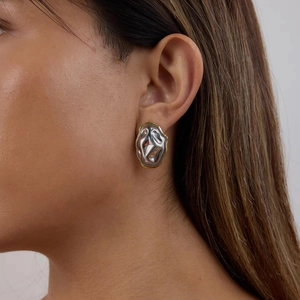 Gros plan de boucles d'oreilles géométriques martelées en or et argent sur un mannequin