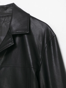 Close-up of lapel and shoulder stitching details on a black coated faux leather jacket