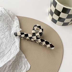 Close-up of a large black and white checkerboard hair claw clip with glossy finish