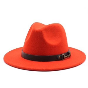 Detailed shot of orange-red fedora hat with black band and golden horsebit buckle