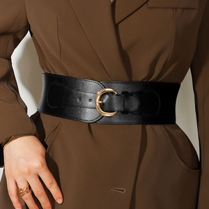 Detail of a wide black elastic waist belt with a gold round buckle on a brown blazer