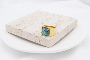 Macro detail of square gold titanium ring featuring colorful abalone shell inlay on stone