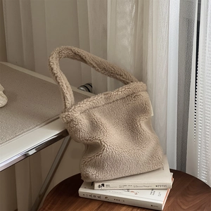 Detailed texture of beige faux fur handbag resting on books in a cozy home setting