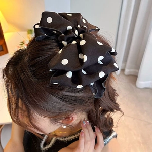 Polka dot bow hair clip shown on model for elegant vintage summer hairstyle