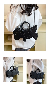 Detail of black dinosaur shoulder bag with silver studs and metal chain strap