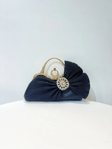 Detailed view of the dark blue pleated fabric and luxury rhinestone clasp of this clutch