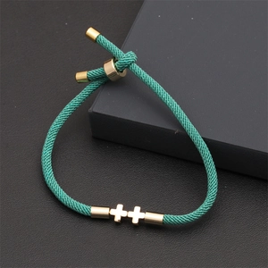 Close-up of green braided adjustable bracelet with dual golden minimalist cross charms
