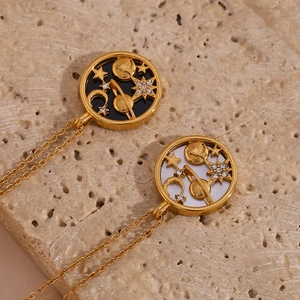 Detail of celestial gold necklaces with star and moon pendants on a beige stone surface