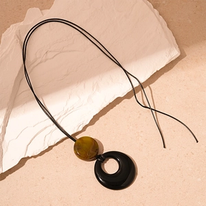 Detail of round resin pendant necklace on white textured stone with marble pattern