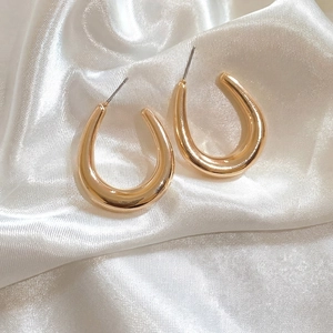 Elegant gold U-shaped hoop earrings with polished mirror finish on white satin background