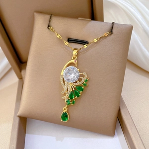 Macro detail of gold peacock pendant with green teardrop stones on jewelry box cushion