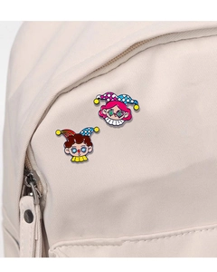 Detail of cute cartoon clown enamel pins attached to a canvas backpack strap