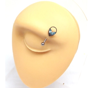 Macro view of heart-shaped eyebrow piercing with blue zircon set on silicone eye model