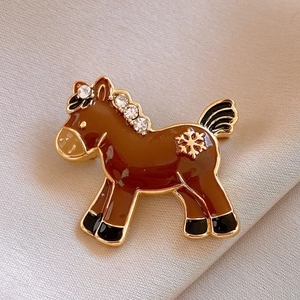 Detailed view of horse brooch with brown enamel, gold plating and crystal accents