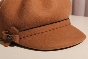 Close-up of brown wool newsboy cap with rhinestone band and bow detail