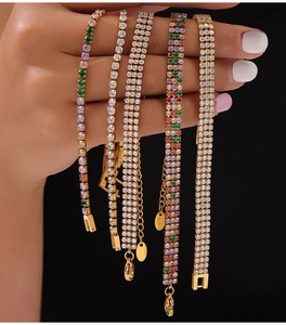 Detail showing various rows of gold-plated tennis bracelets with rainbow and white cubic zirconia