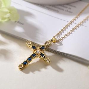 Detail of gold cross pendant with blue marquise stones and round zircons on a book