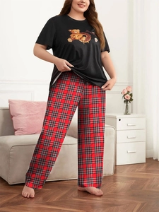 Dettaglio pantaloni scozzesi rossi e maglietta nera con grafica fragola pigiama