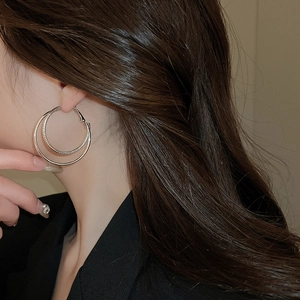 Detail of layered gold hoop earrings with textured inner ring worn by a model