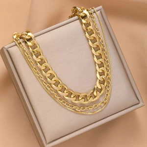 Three-layer layered gold metal chain necklace displayed on a beige jewelry presentation box
