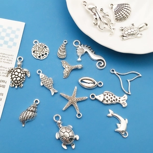 Detail of silver alloy ocean charms including starfish and sea turtle on blue background