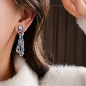 Gros plan de boucles d'oreilles vintage à pompons avec pierre rose et cristaux bleus