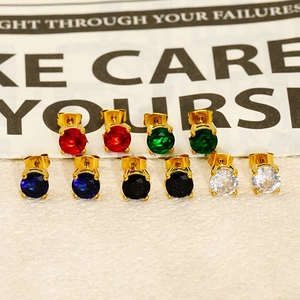 Detail view of multicolored zircon stud earrings in gold settings on vintage newspaper