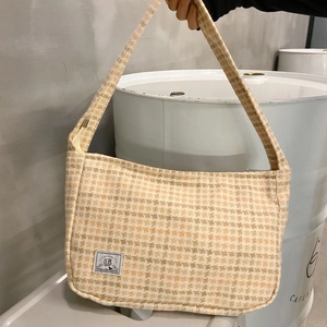 Detail of orange and beige checkered tweed shoulder bag showing weave texture and SR label
