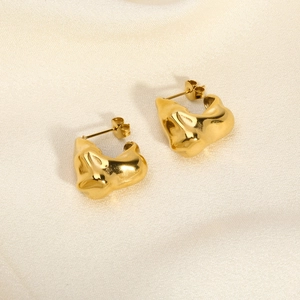 Macro shot of gold-plated V-shaped irregular earrings with molten metal texture on silk