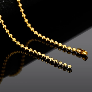 Close-up of golden stainless steel ball chain necklace with polished metallic finish