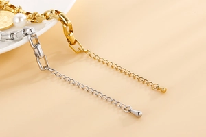 Détail de la chaîne géométrique or et argent avec pendentif goutte sur fond chaud