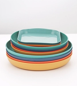 Close-up of stacked wheat straw plates in multiple colors with ribbed texture details