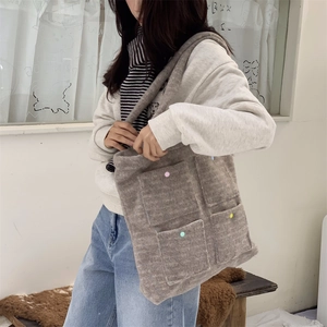 Detail of grey plush tote bag with four colorful buttoned pockets for autumn wear