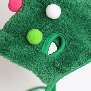 Detail of green plush pet hat with colorful poms and ear holes for dogs and cats