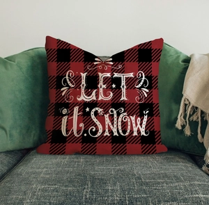 Detail of red black buffalo plaid pillow with white LET IT SNOW text on grey sofa