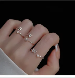 Detail of silver letter rings H, V, W with zircon inlay on model finger in high contrast