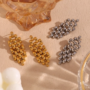 Detailed view of woven chain link earrings in gold and silver plating on textured surface