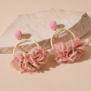 Close-up of pink fabric flower and woven geometric hoop earrings for women