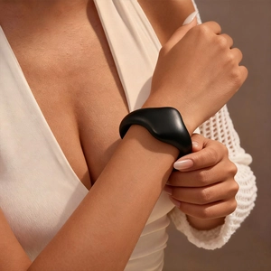 Detail of wide matte black asymmetric geometric cuff bracelet on model's wrist