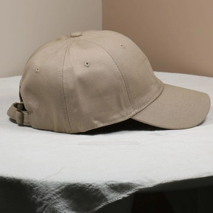 Side view of khaki baseball cap featuring metal buckle adjustment and embroidered eyelets