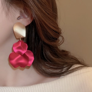 Detail of rose red leaf petal drop earrings with gold studs worn by a model