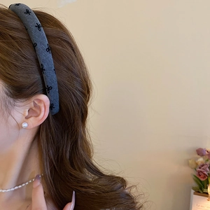 Close-up of gray fabric headband with black bow patterns shown on a model side view