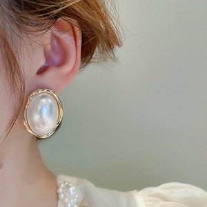Gros plan de boucles d'oreilles perles baroques avec monture en métal doré texturé