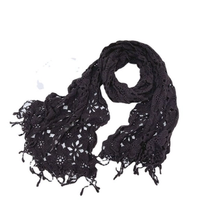 Detailed close-up of a black knit lace scarf with intricate floral embroidery and long tassels