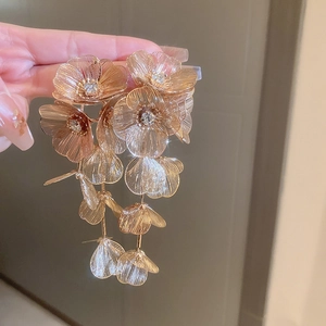 Macro shot of gold floral tassel earrings with hollow wire petals and clear rhinestones
