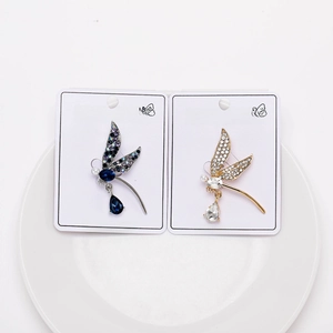 Close-up of gold and silver dragonfly brooches with rhinestones and pearls on a white plate