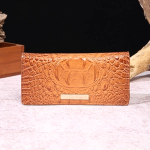 Close-up of brown crocodile texture leather wallet with metallic gold trim on marble