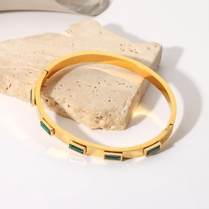 Détail d'un bracelet en titane doré orné d'un zircon rectangulaire vert émeraude