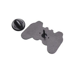 Detail view of a metal game controller brooch showing the back pin and black rubber clutch